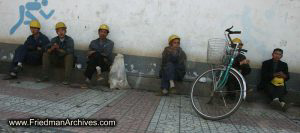 Construction workers sitting next to wall